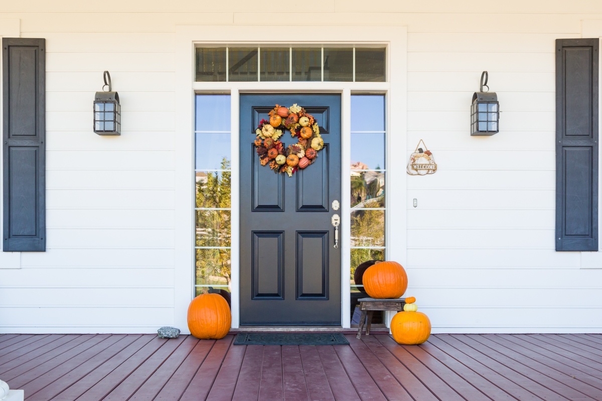 fall wreath and pumpkins on front door on porch