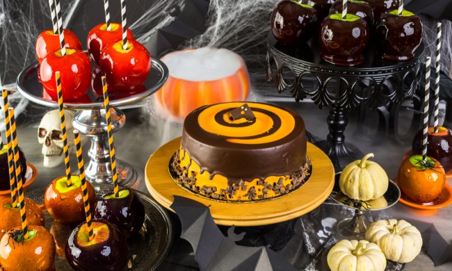 Table with colored candy, apples, and cake for Halloween party