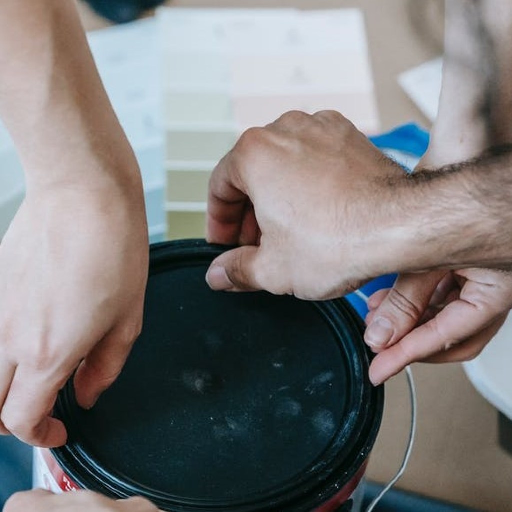 hands covering paint can