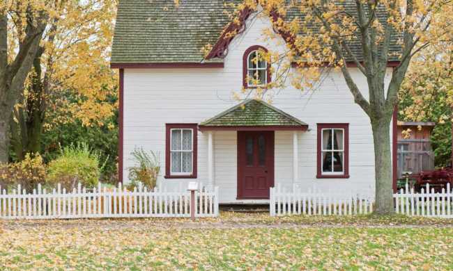 White two-story house with autumn leaves in the front yard