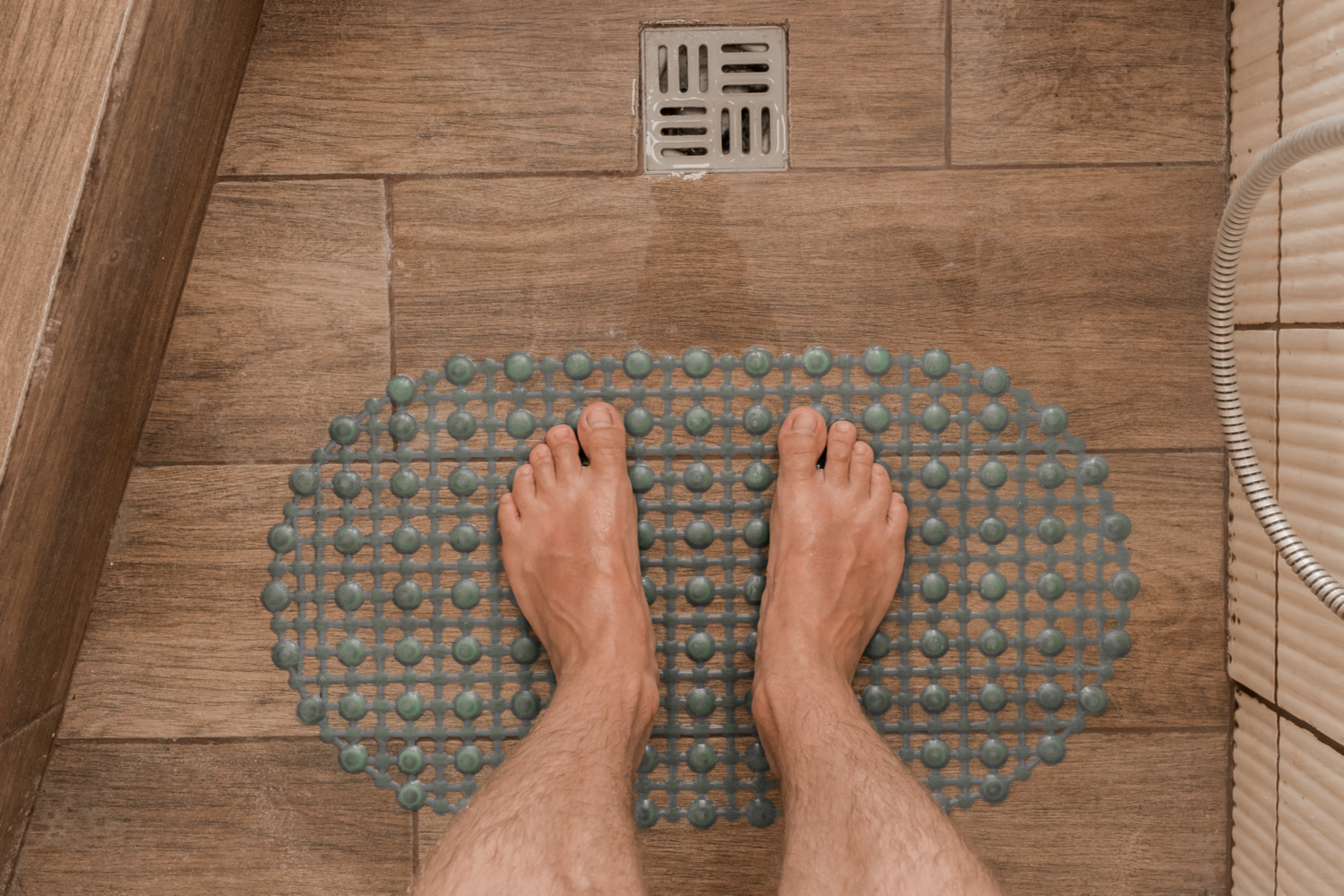 Bath mat and shower drain on wood-look shower tiles