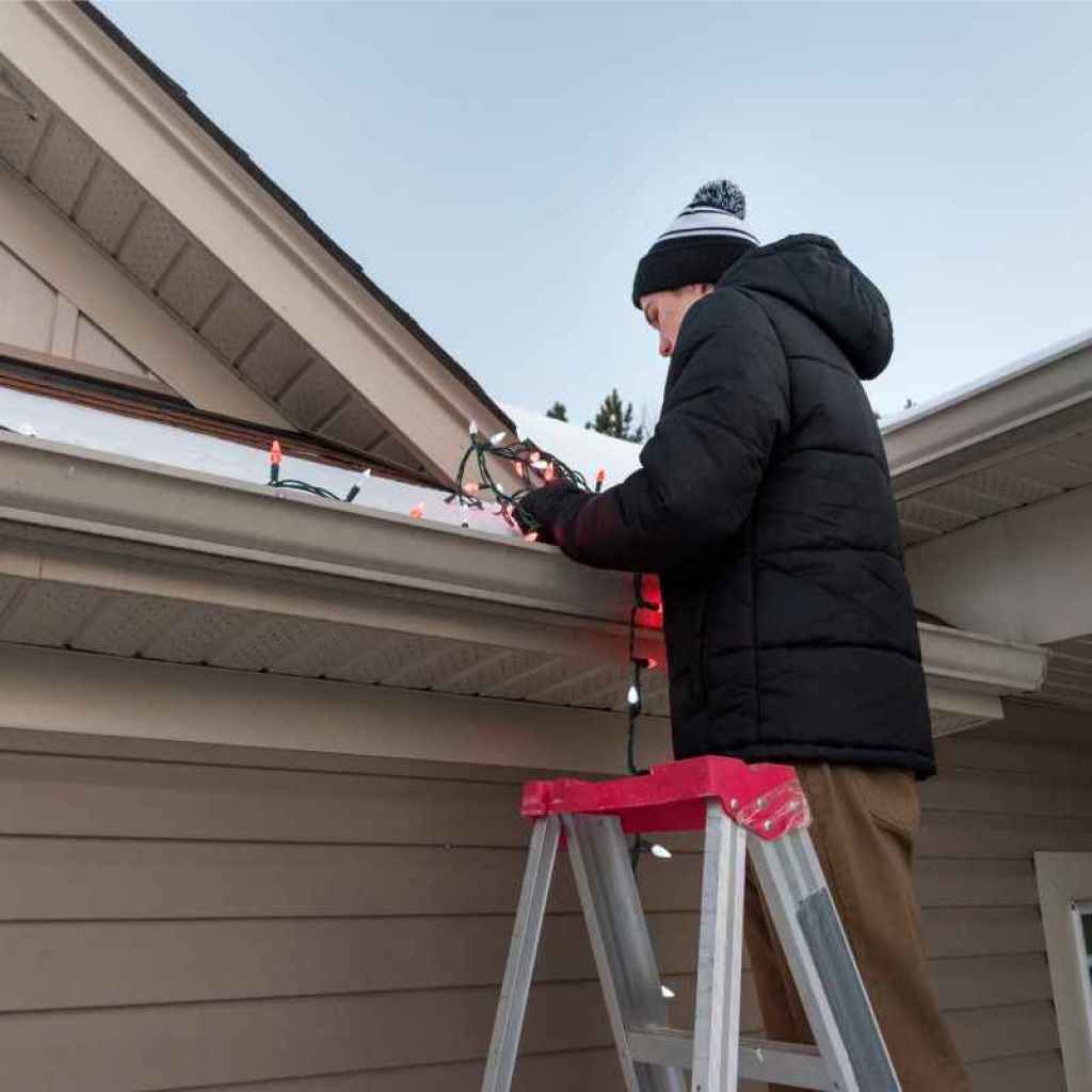 Man hanging Christmas light on the roof