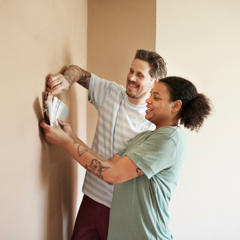 couple comparing paint swatches on the bedroom wall