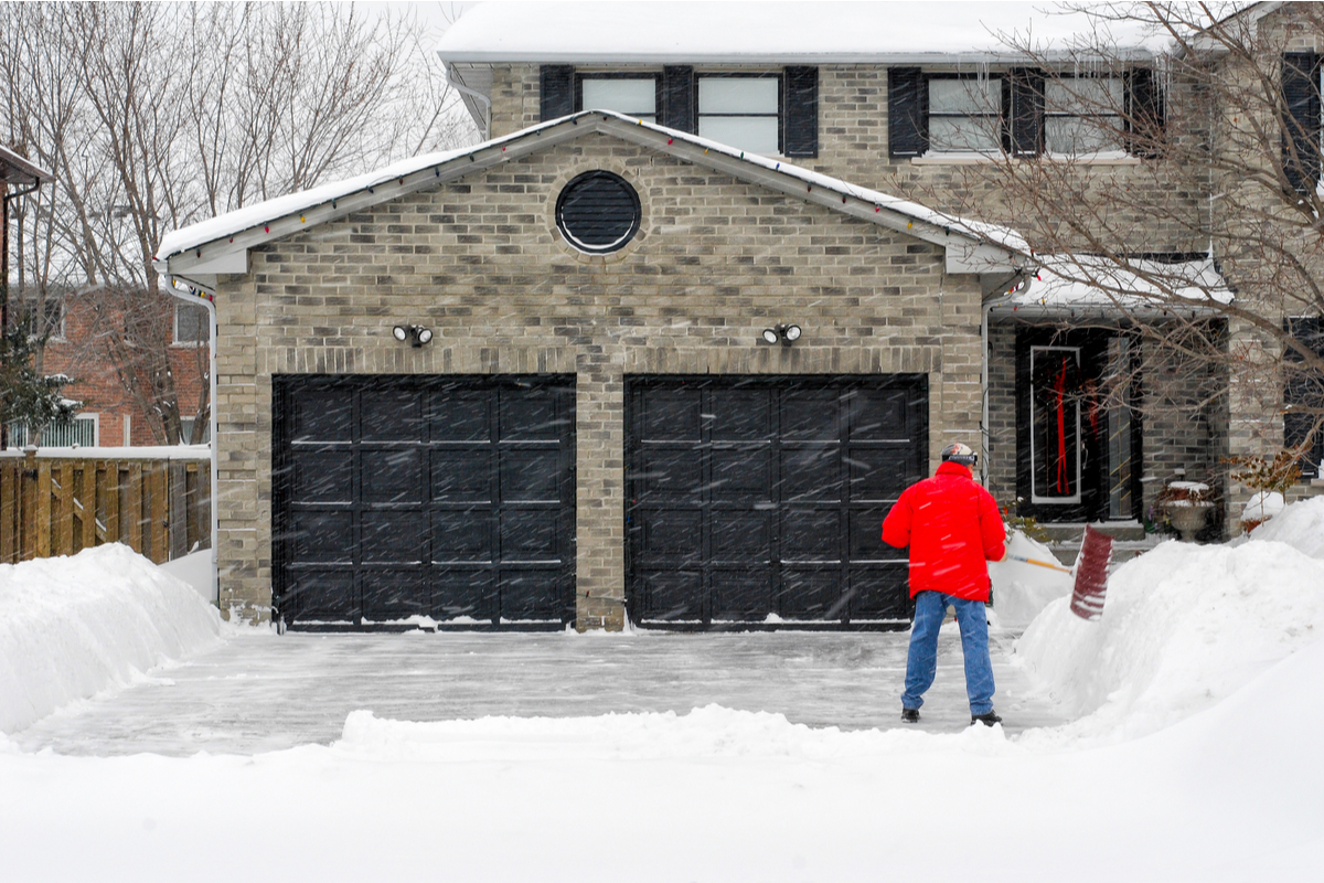 Garage and driveway with man shoveling snow