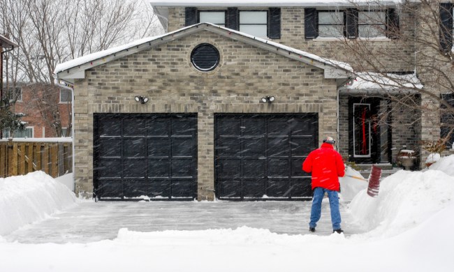 Garage and driveway with man shoveling snow