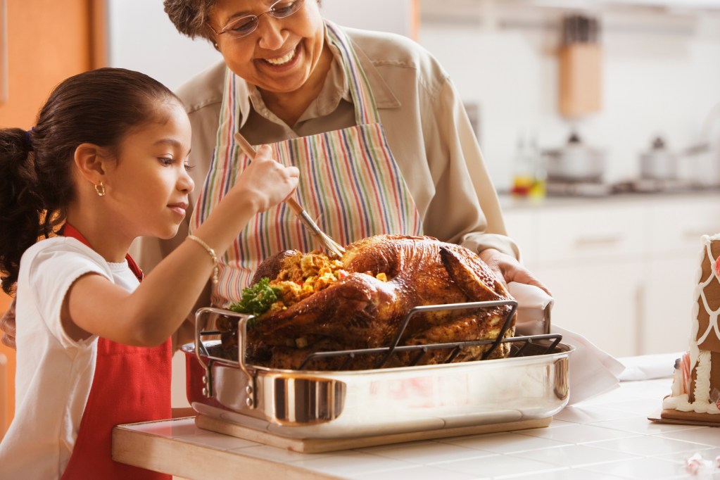 grandmother helping child with thanksgiving turkey