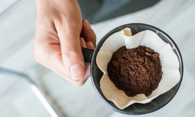 Person holding coffee filter with coffee grounds.