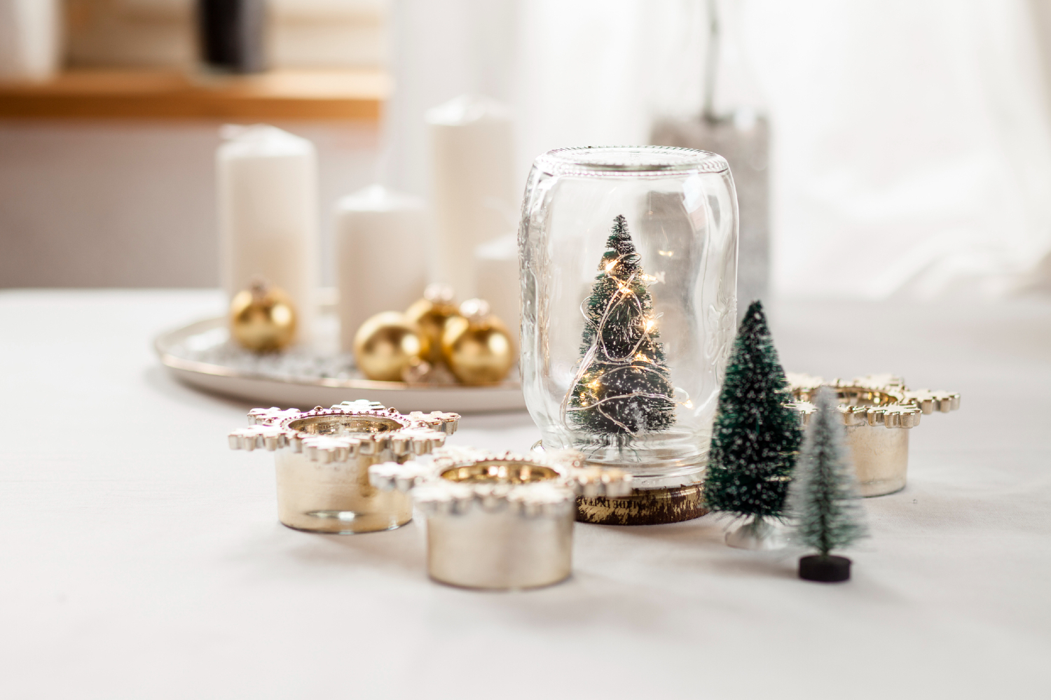 Modern christmas decorations with candles, bulbs, and small trees.