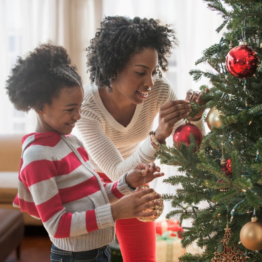 a mother and daughter decorate a christmas tree together