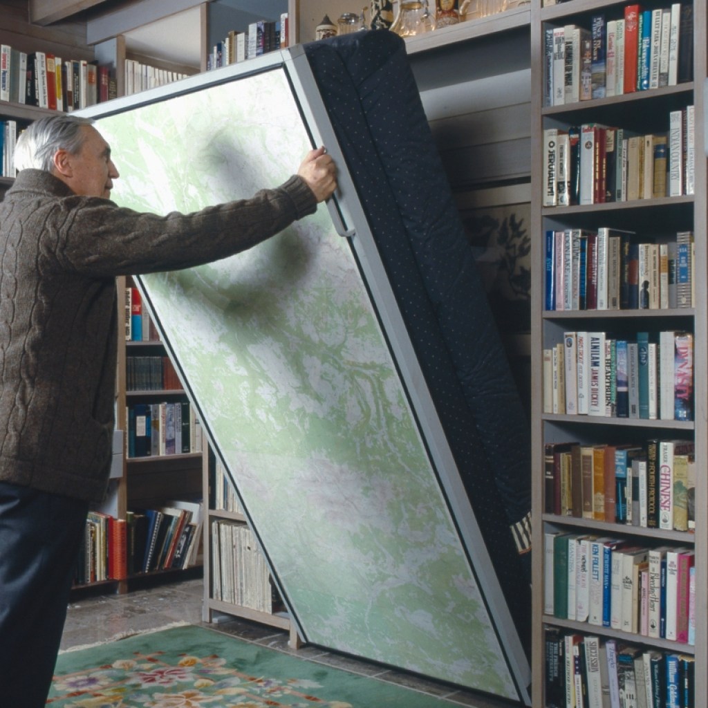 elderly man lowering a murphy bed in home office