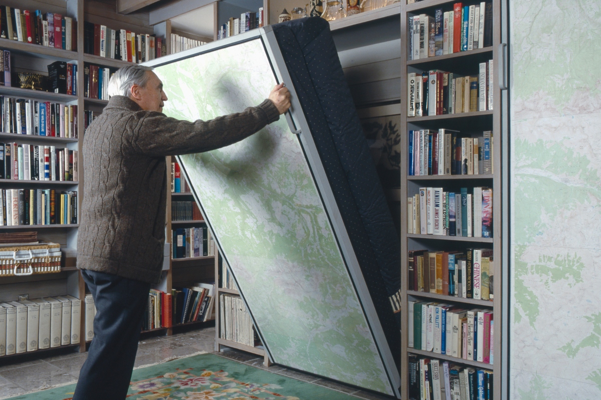 elderly man lowering a murphy bed in home office
