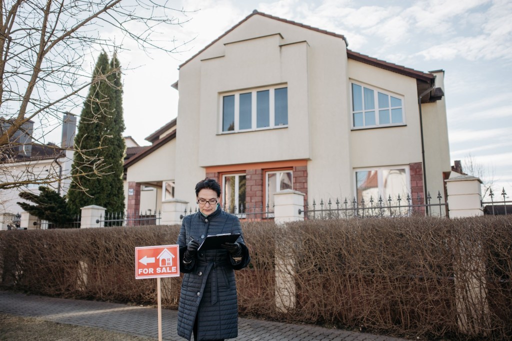 Real estate agent in front of a house for sale