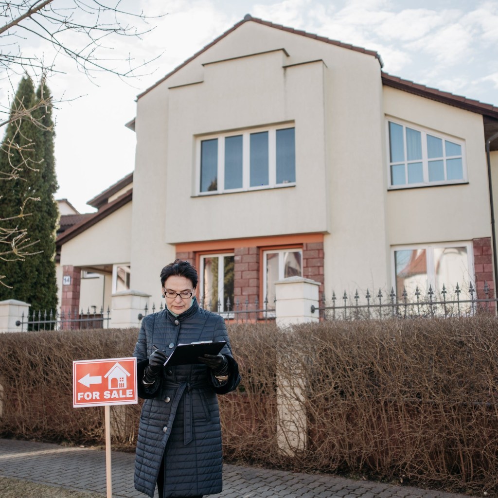 Real estate agent in front of a house for sale