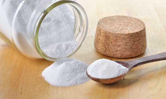 Glass jar of baking soda with cork and teaspoon tipped over