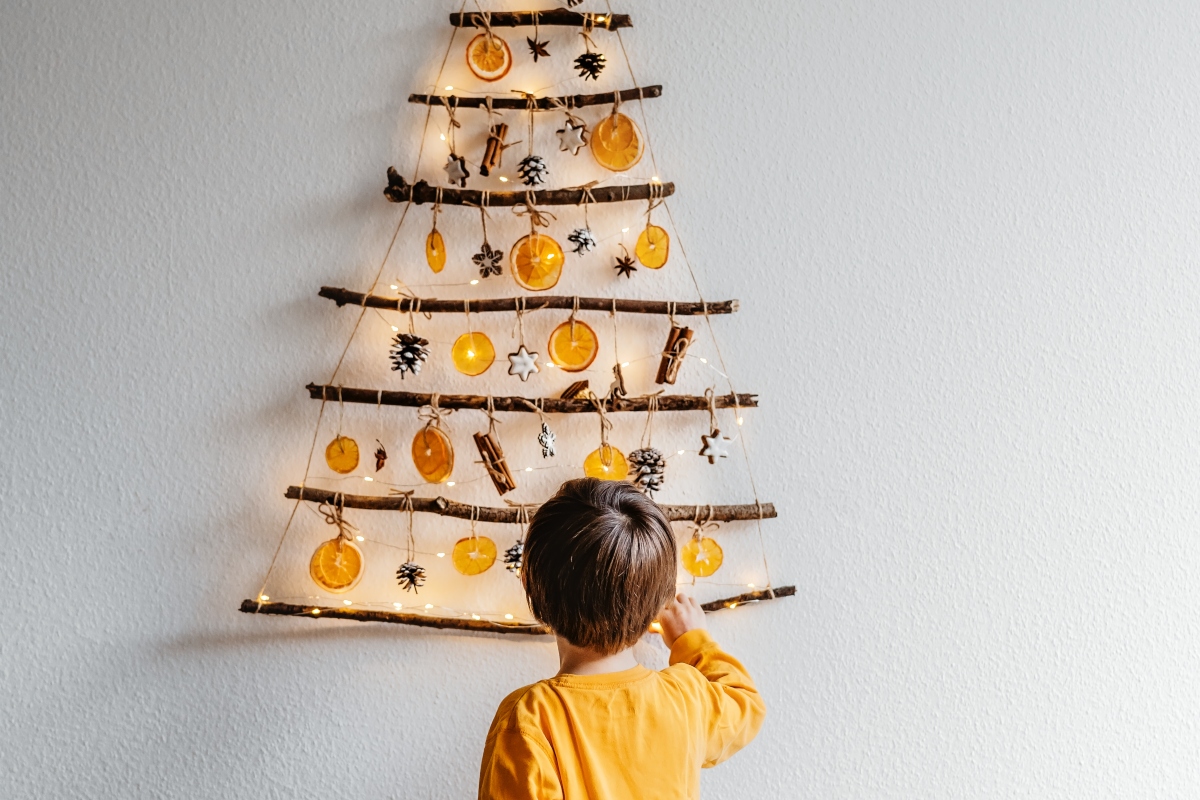 child putting up DIY wall-mounted christmas tree