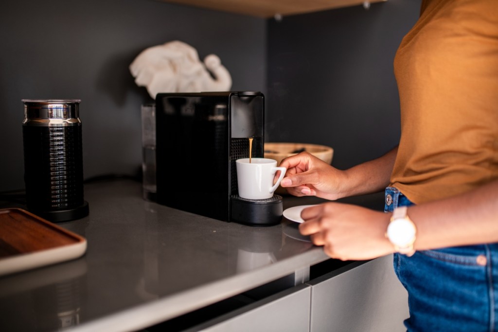 Person using a compact coffee maker on a kitchen counter