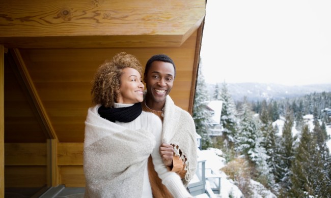 Couple sharing a blanket on a snowy winter balcony