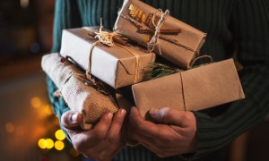 Person holding gifts wrapped in brown paper.