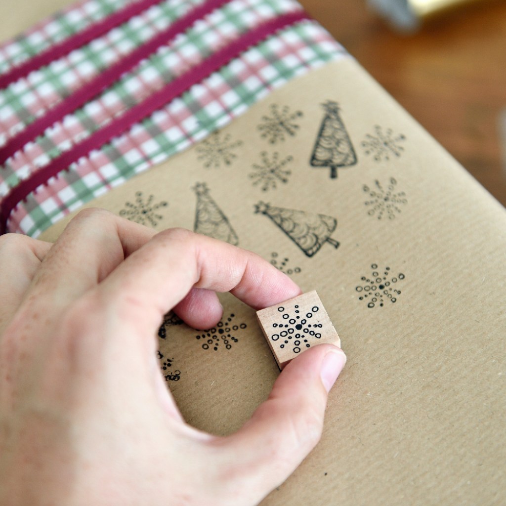 Person decorating gift with rubber stamp.