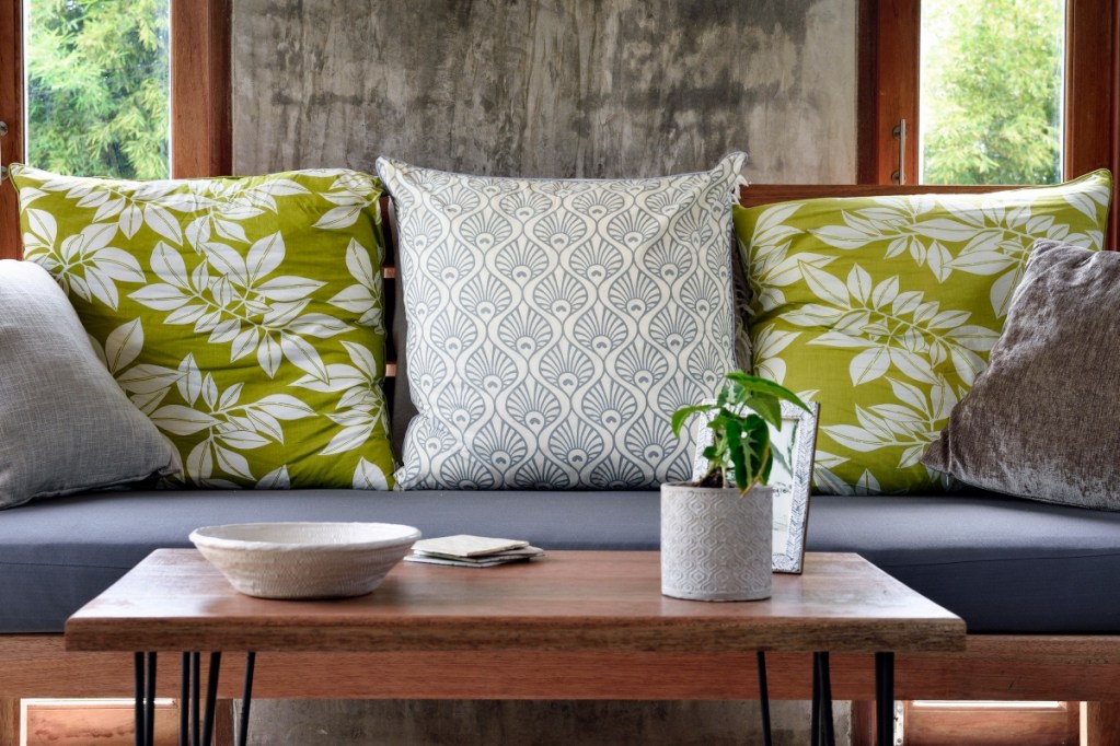 Living room sofa with green and white pillows with a wood coffee table