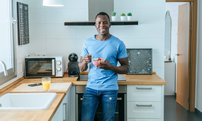 Man eating food in a kitchen with blue walls
