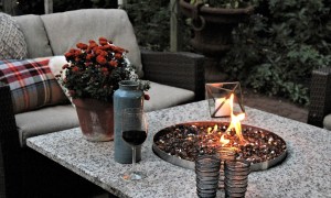 Outdoor propane gas fire pit with fall flowers and drinks