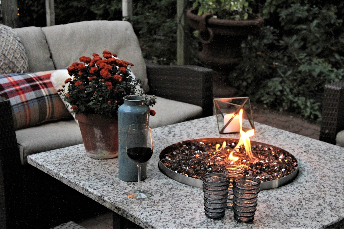 Outdoor propane gas fire pit with fall flowers and drinks