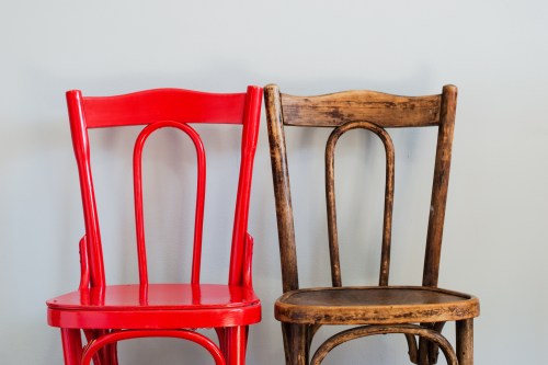 Two wooden chairs next to each other: one is painted red and one is natural wood