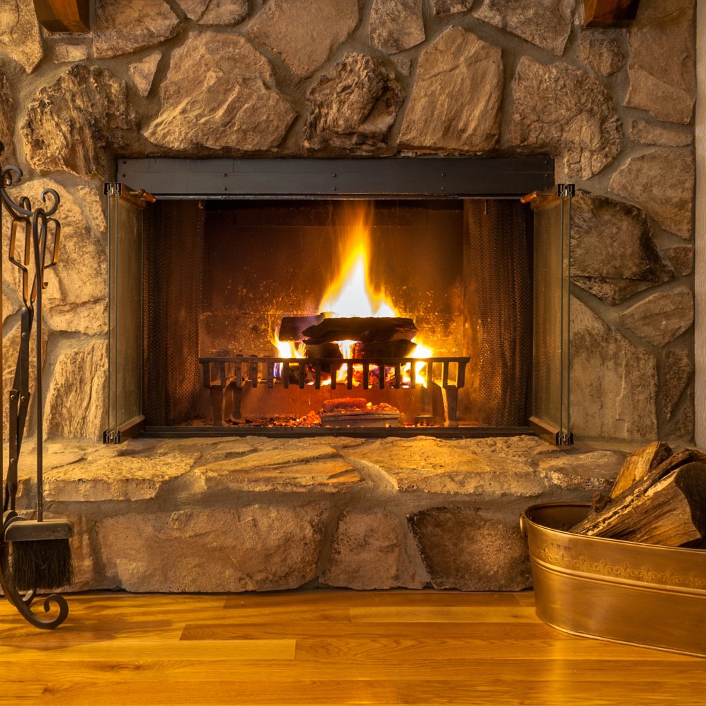 lit fireplace with rack of tools and bin of wood