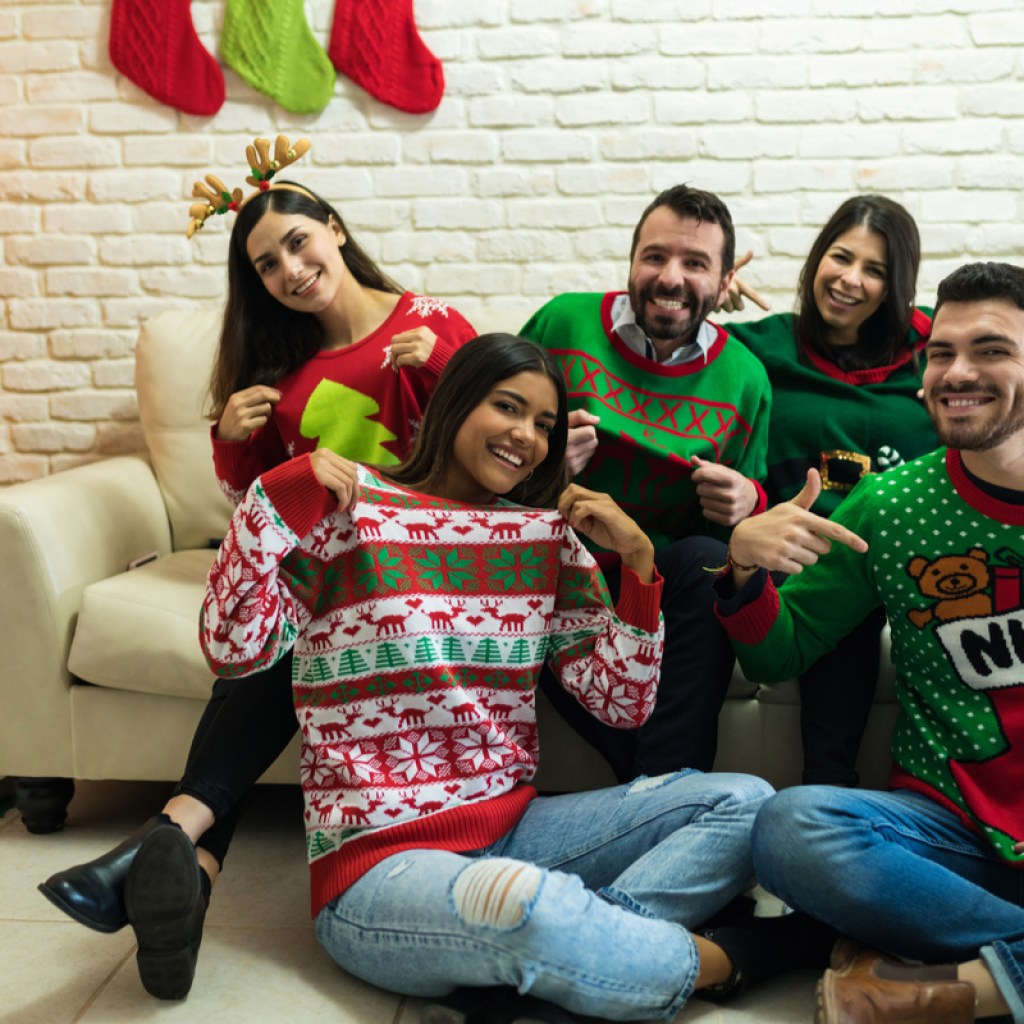 Group of people wearing ugly Christmas sweaters in a living room