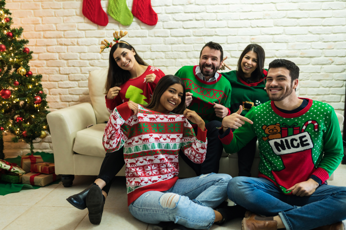 Group of people wearing ugly Christmas sweaters in a living room