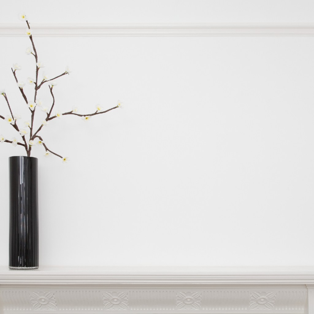 All-white mantle with black vase.