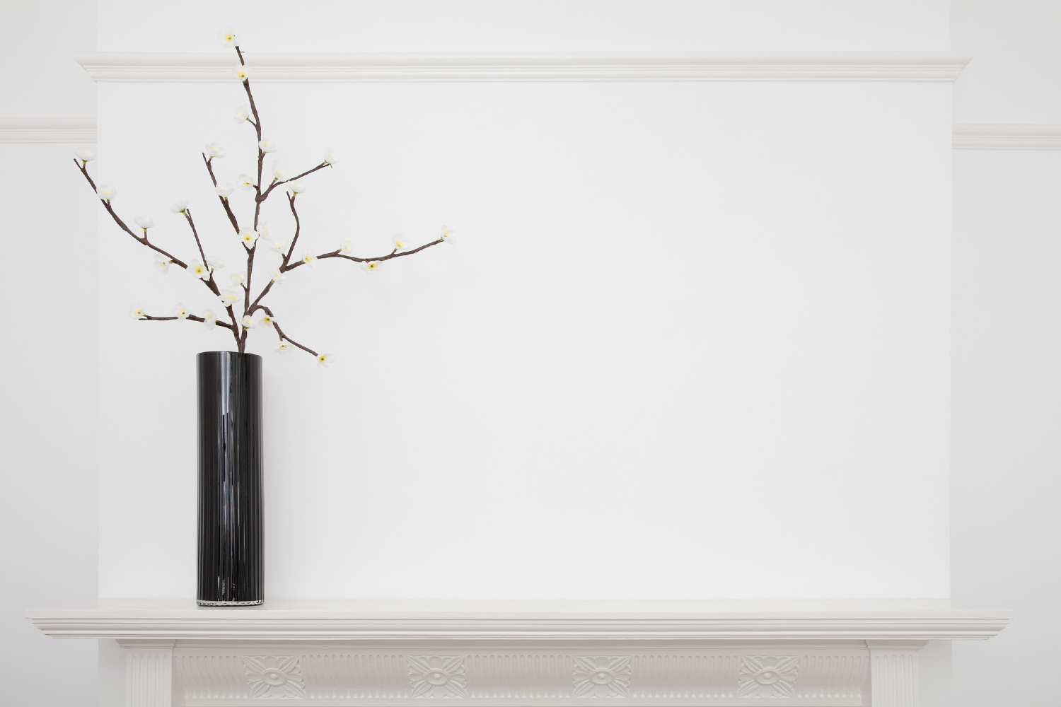 All-white mantle with black vase.