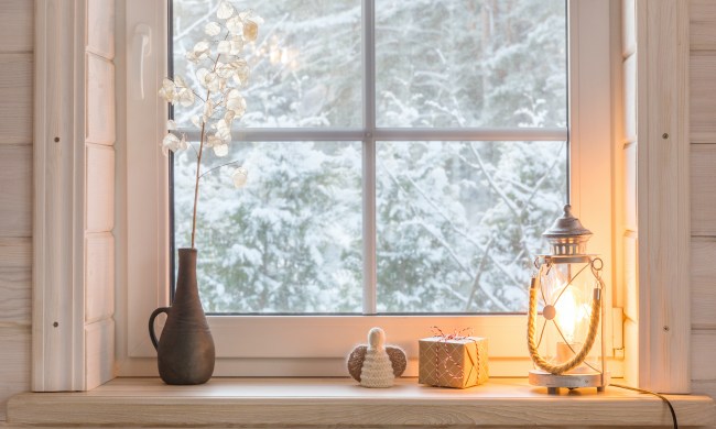 Beautiful burning candles and fairy lights on windowsill indoors with vase