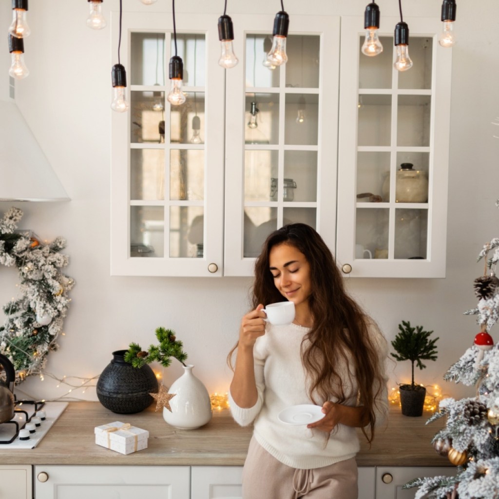 Woman drinking coffee in rustic kitchen with a Christmas tree