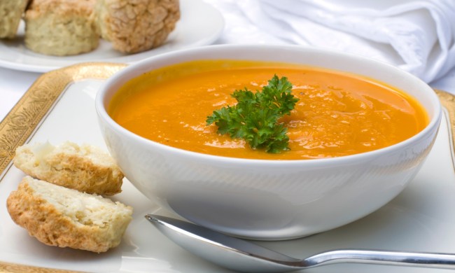 carrot soup in white bowl with side of bread