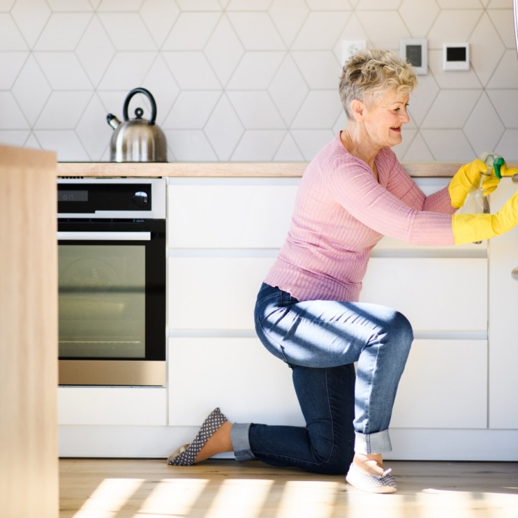 an elderly woman disinfects and cleans the refridgerator