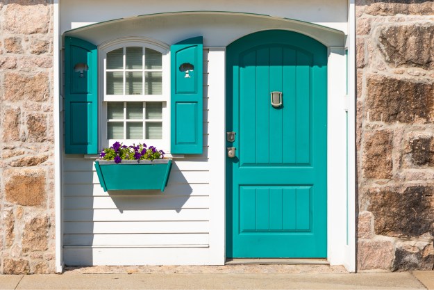 teal front door of small white cottage