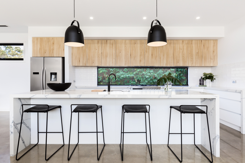 White modern kitchen with black pendant lights and black stools