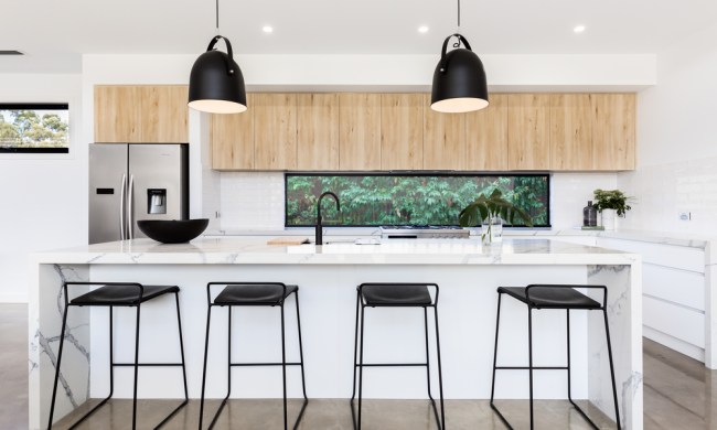 White modern kitchen with black pendant lights and black stools