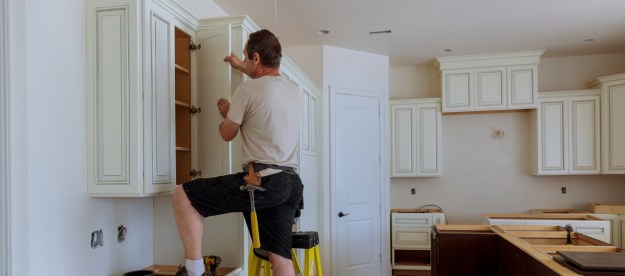 man installing white kitchen cabinets
