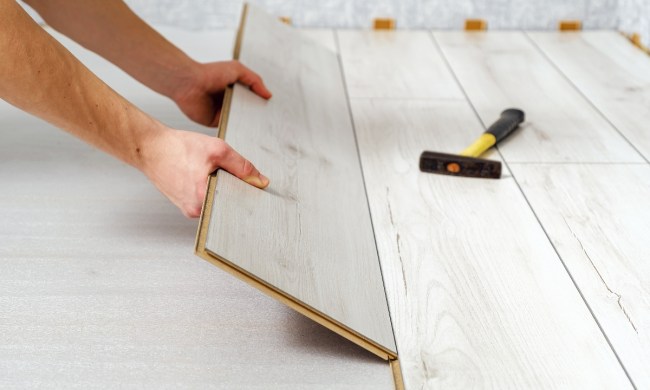 Person laying down laminate flooring in basement
