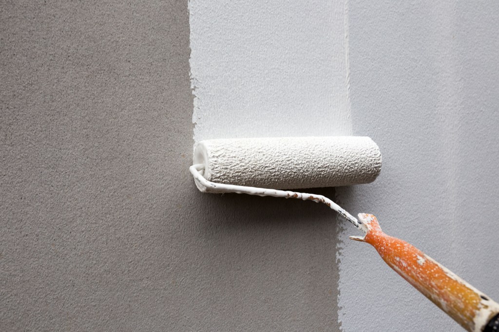 Person using paint roller to coat a textured wall
