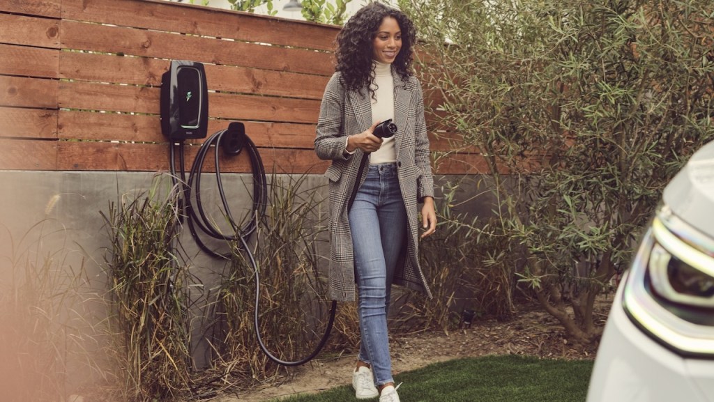 Young woman walking to EV with charging cord