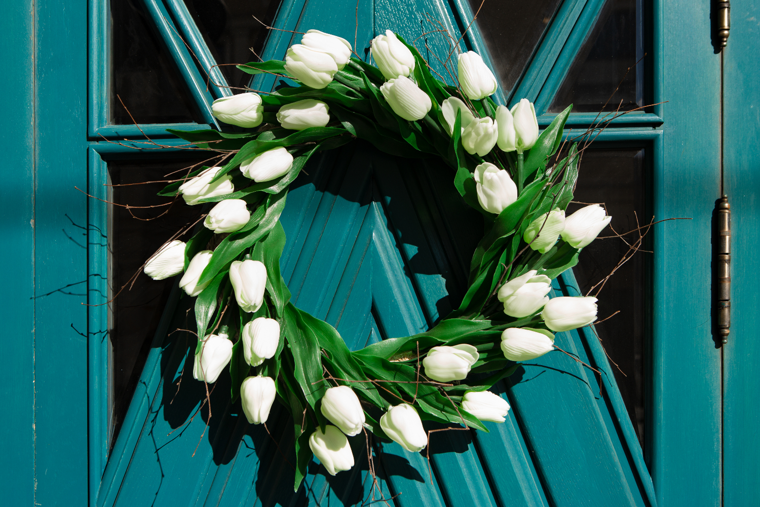 Spring wreath made from white flowers on a teal door