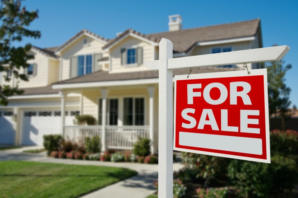 Cream-colored suburban home with for sale sign