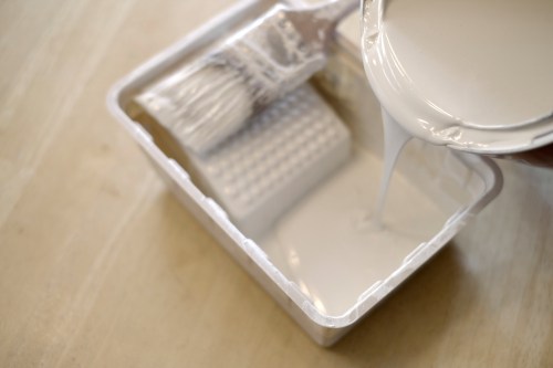 Pouring cream paint into a paint tray