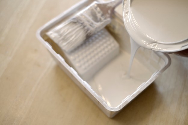 Cream paint being poured into a paint tray