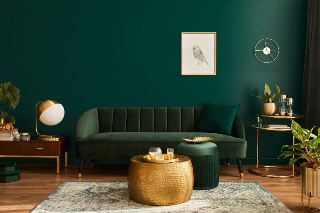 dark green living room with green sofa and gold details