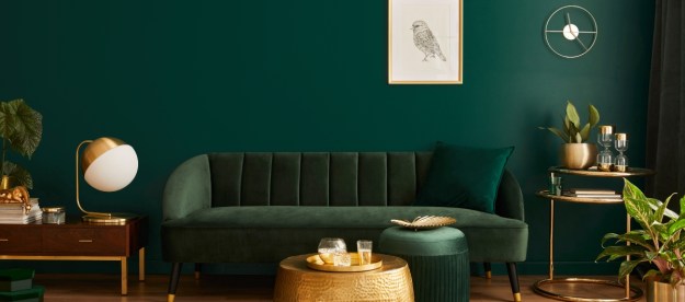 dark green living room with green sofa and gold details